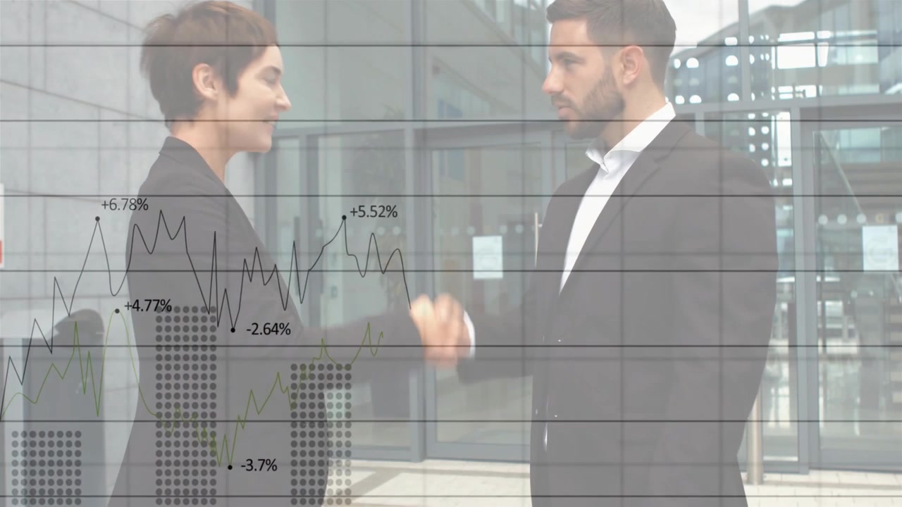 Coppia in abito avvia una discussione, parlando e gesticolando nella hall riguardo a grafici finanziari, concludendo con una stretta di mano.