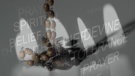 Multiple-religious-words-against-burning-candle-and-Christian-rosary-falling