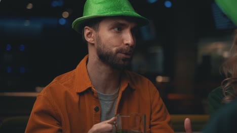 retrato de un hombre barbudo con sombrero irlandés hablando con amigos en un pub