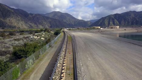 Aerial-flyover-of-a-long-conveyor-of-rocks-along-a-riverbed-extending-out-into-the-distance