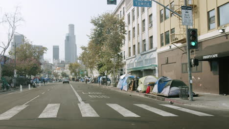 homeless encampment along a city street with downtown los angeles skyline