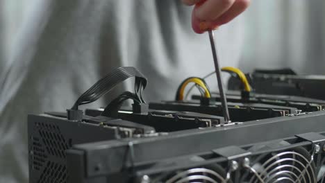 cerca de la mano del hombre atornillando el tornillo en la plataforma de minería para la minería de criptomoneda