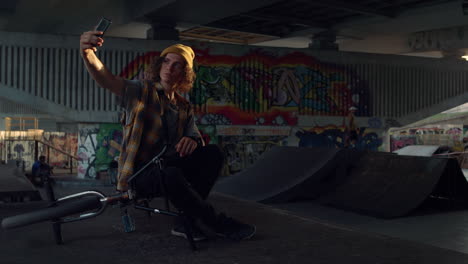 teen making selfie photo on mobile phone at skate park graffiti wall background.