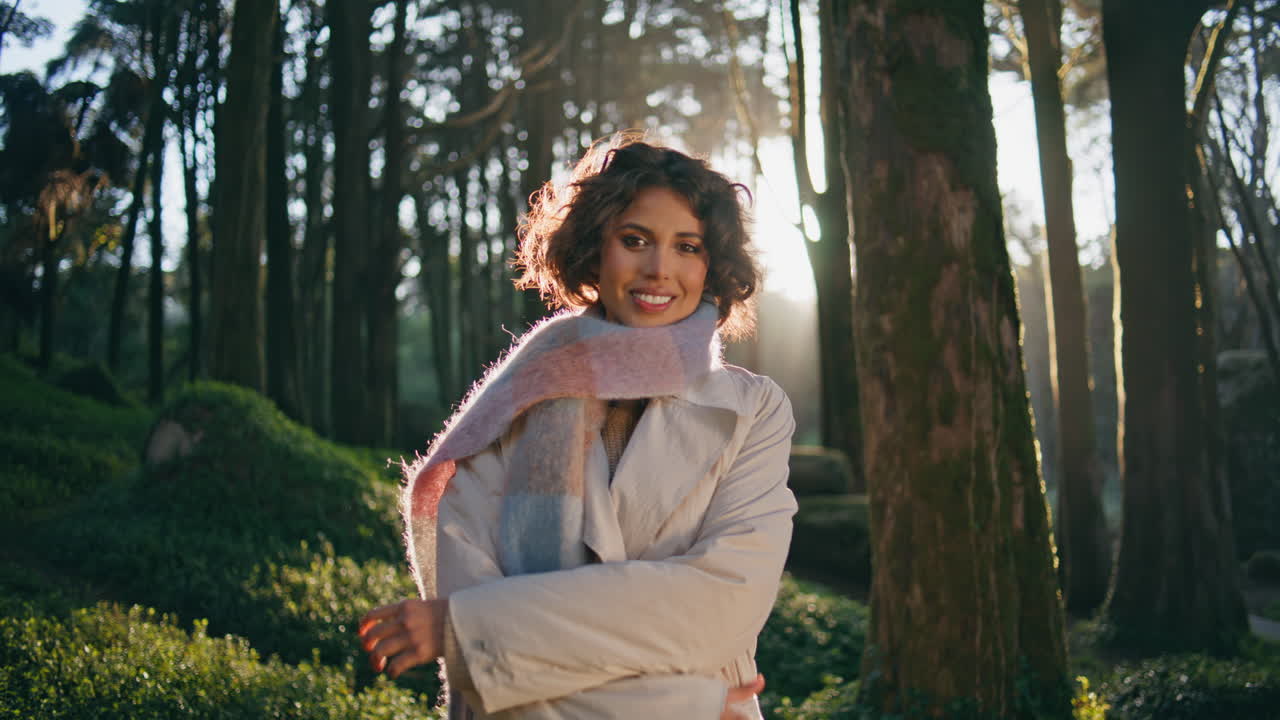 niña de pie en el jardín a la luz del sol en una bufanda chic que exuda felicidad y estilo de primer plano.