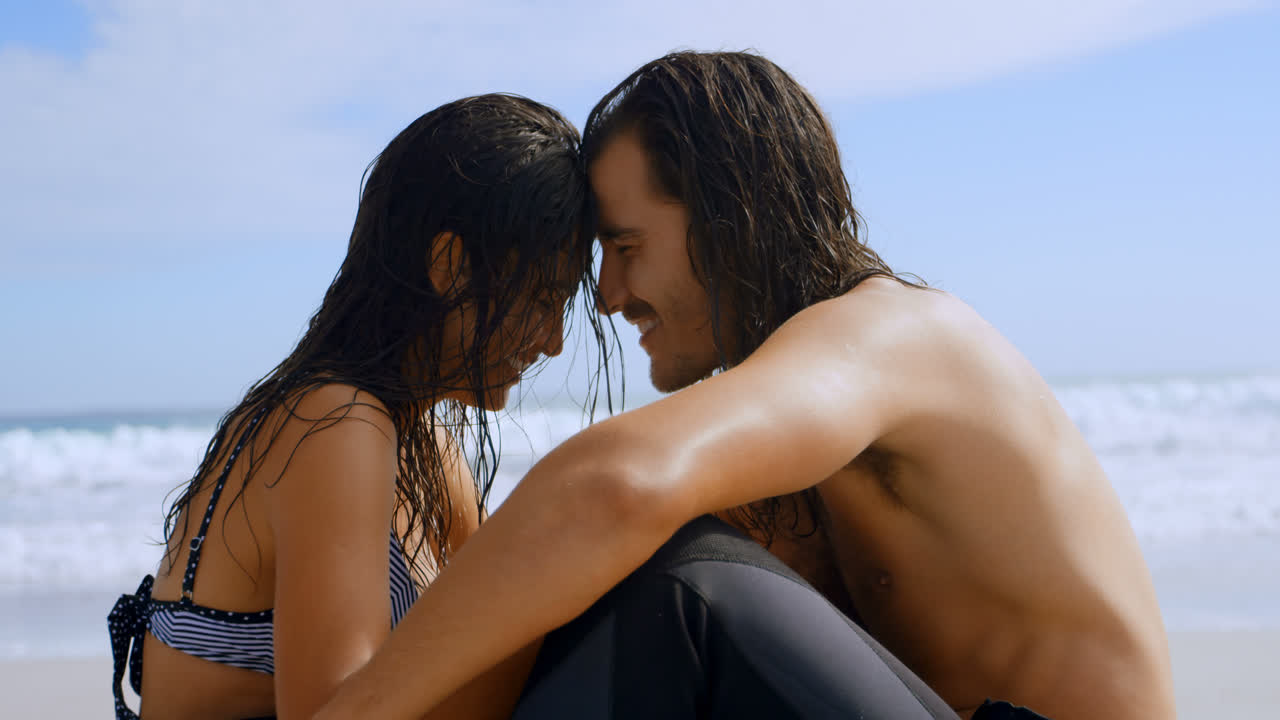 Surfer couple talking on the beach 4k