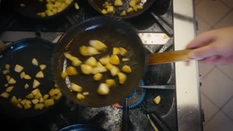 Top-down-footage-of-potatoes-being-fried-on-a-pan-in-a-commercial-kitchen