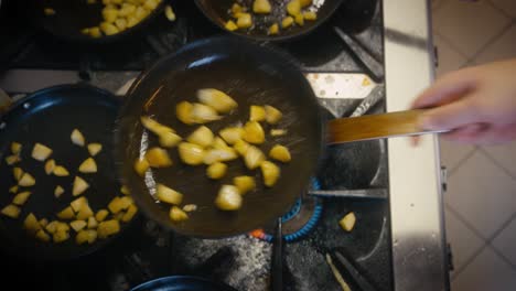 top down footage of potatoes being fried on a pan in a commercial kitchen