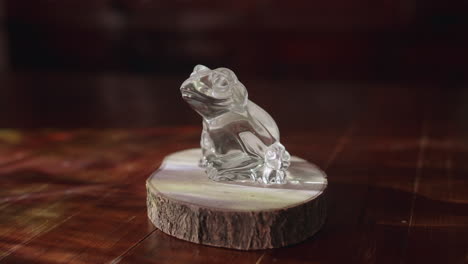 small crystal frog ornament sitting on a fake log