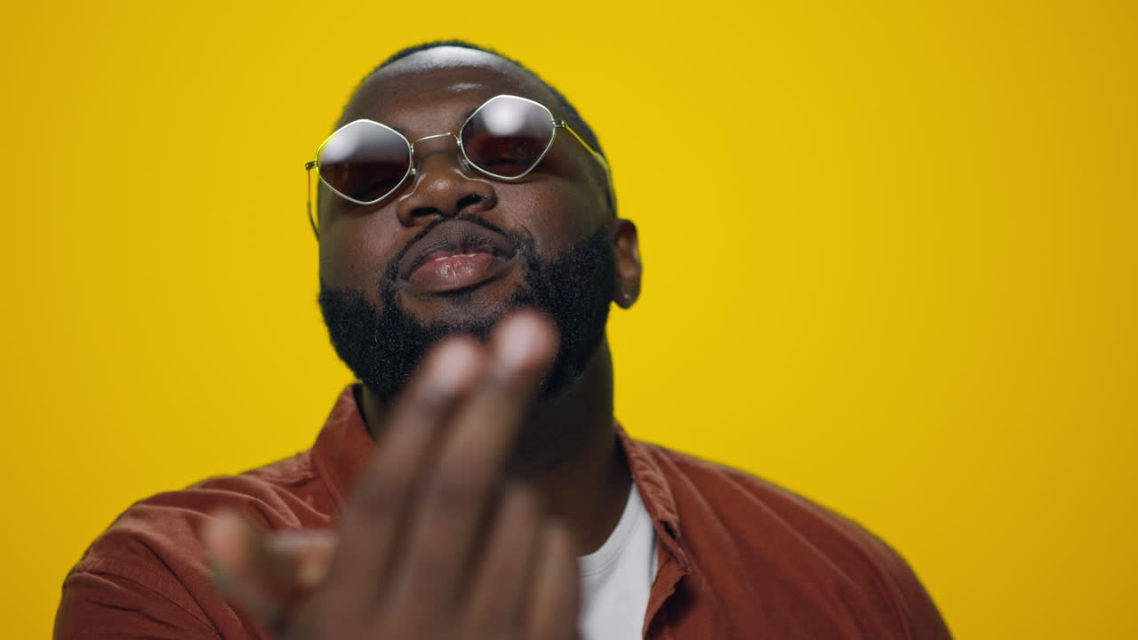 retrato de un hombre afroamericano sonriente mostrando el gesto de venir a mí en el estudio.