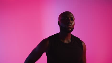 retrato de estudio en primer plano de un jugador de baloncesto masculino driblando y rebotando la pelota contra un fondo iluminado de color rosa 2