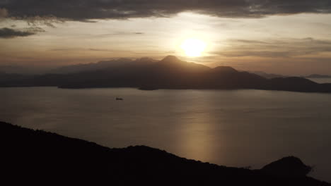 Aerial-Landscape-of-Cliffs-and-Ocean-with-Ship-in-Da-Nang,-Vietnam-at-Sunset