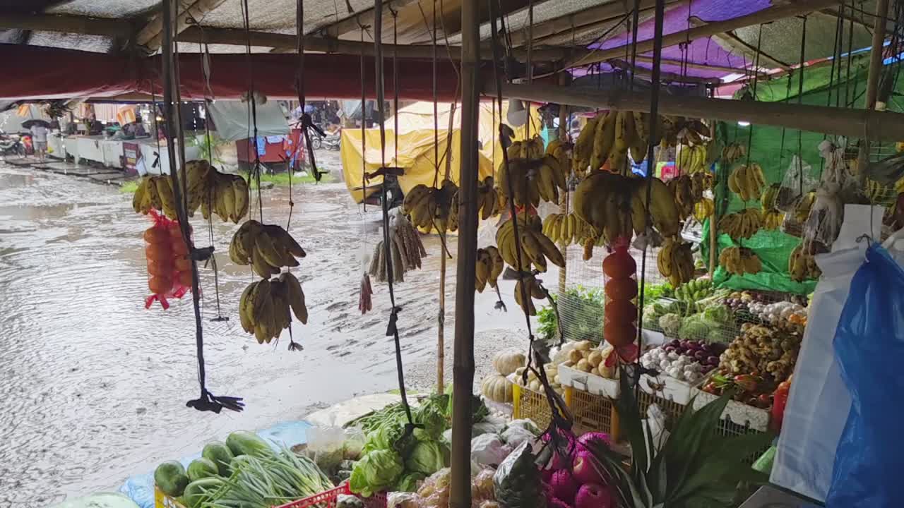 Crowded Dumaguete vegetable market on a rainy, muddy day in the Philippines with wind blowing hanging fruits and plastic bags, slow motion