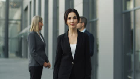 blurred shot of mature businesswoman leaving business partners and coming closer to camera in the street 1