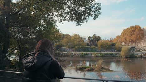 Una-Chica-Tomando-Fotos-De-Un-Lago-En-El-Parque-Temprano-En-La-Mañana,-Montpellier---Francia