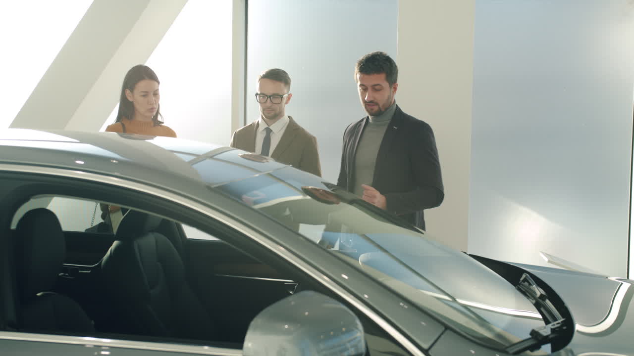 Car Salesman Discussing a Vehicle with Customers in a Showroom