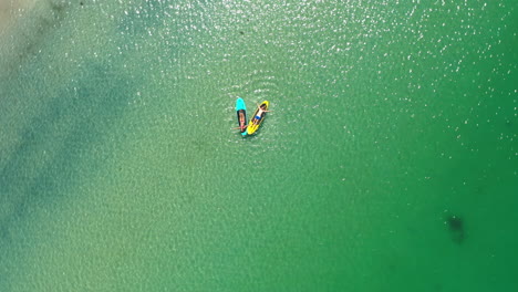 aerial view of two people paddleboarding in clear green water