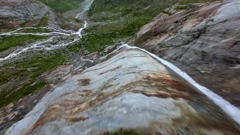 freestyle drone flight over water stream flowing at fellaria glacier in valmalenco of valtellina, italy