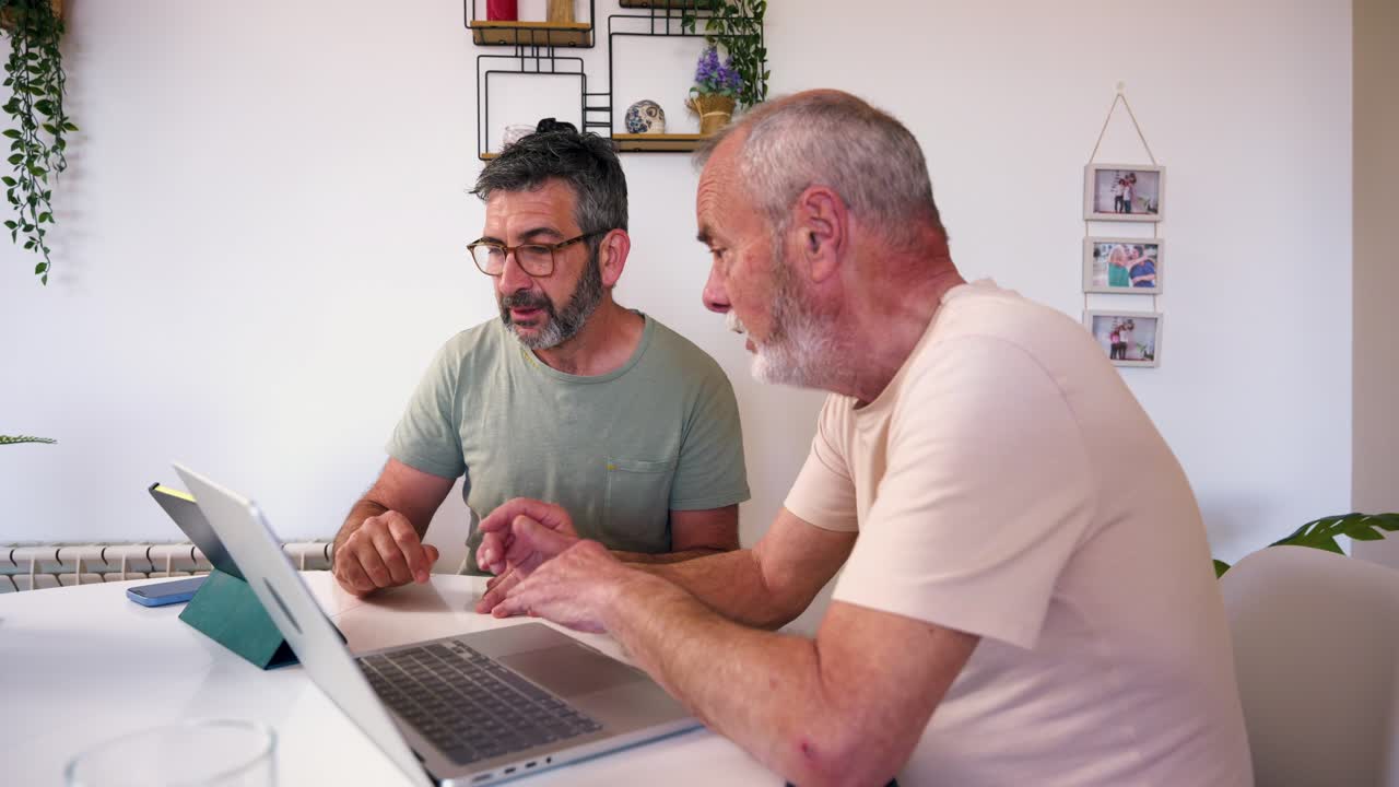 Two Men Discussing and Working Together on a Laptop at Home