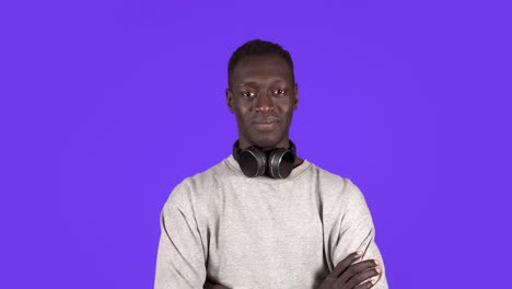 Un-Joven-Atractivo-Con-Auriculares-En-El-Cuello-Y-Una-Camisa-Blanca-Asiente-Con-La-Cabeza-Positivamente-Aislado-Sobre-Fondo-Azul