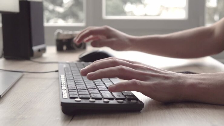 Tippen auf einer Tastatur. Mann tippt auf Computertastatur. Männerhand benutzt Computertastatur und Maus zum Tippen. Freiberuflicher Fotograf arbeitet am Computer.