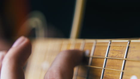 musician plays brown acoustic guitar and improvises closeup