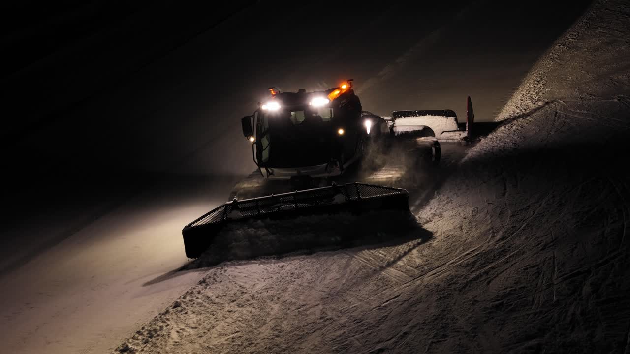 Gatto delle nevi che lavora di notte nelle Dolomiti, Alpi italiane, con luci intense e una scia ben definita dietro di sé