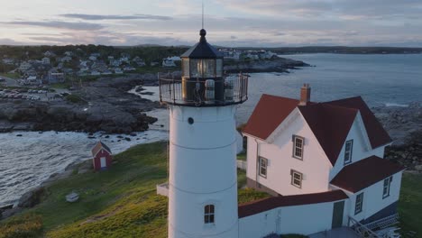 Aerial-Drone-shot-of-York-Beach-Maine-flying-around-Cape-Neddick-Nubble-Lighthouse-at-Sunset