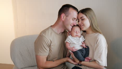 portrait of a happy caucasian family with newborn boy. loving parents hold their sleeping baby leaning to him from two sides.