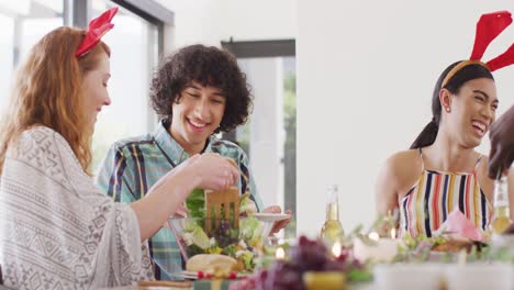 happy group of diverse friends sitting at table and eating dinner together