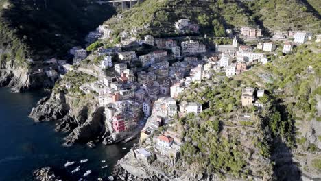 la ciudad italiana de riomaggiore en la costa de cinque terre con edificios construidos en un acantilado, drone aéreo dolly izquierda revela disparo