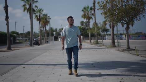 man walking on a city street with palm trees