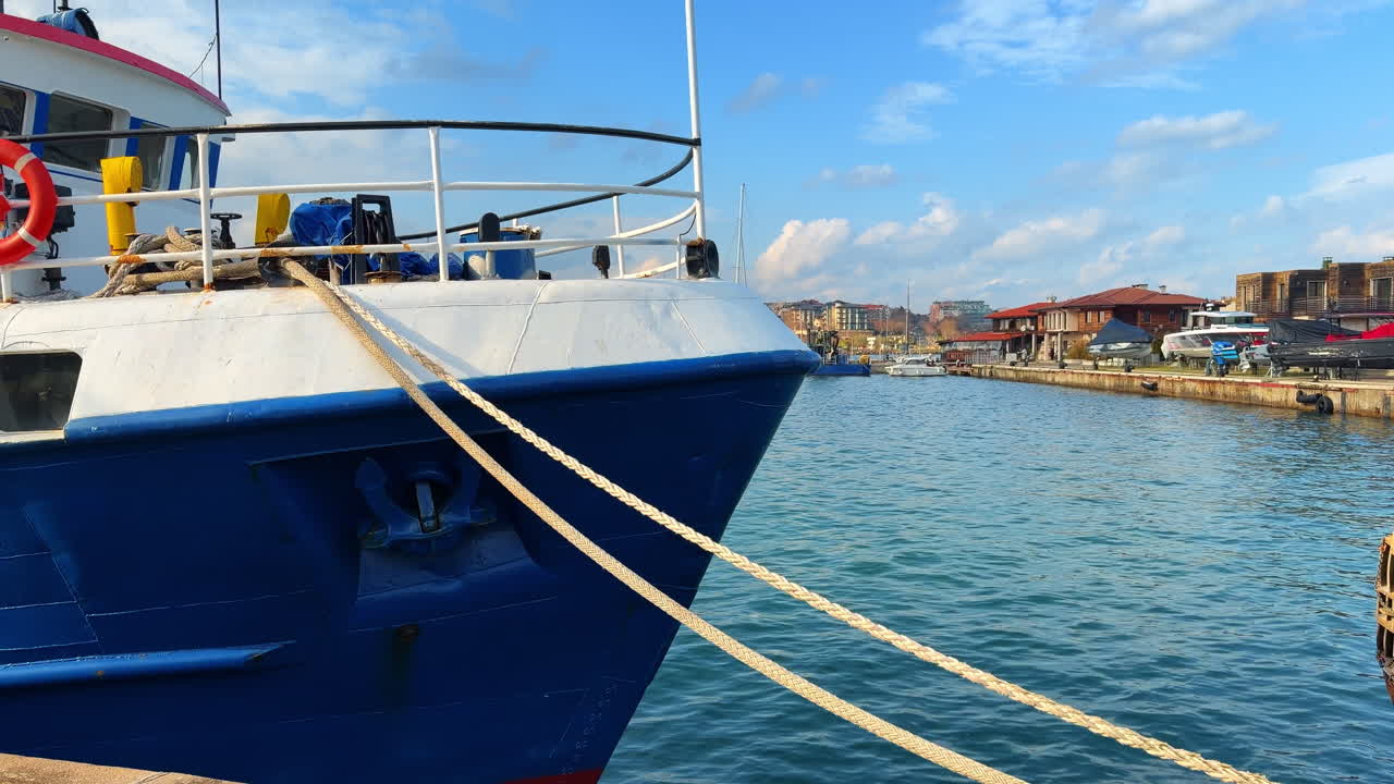 Burgas, Bulgaria, 29 ottobre 2025: barche ormeggiate sul lungomare sotto il cielo azzurro e le nuvole nel porto. Le barche sono legate al molo in un porto affollato, con edifici e acqua visibili.