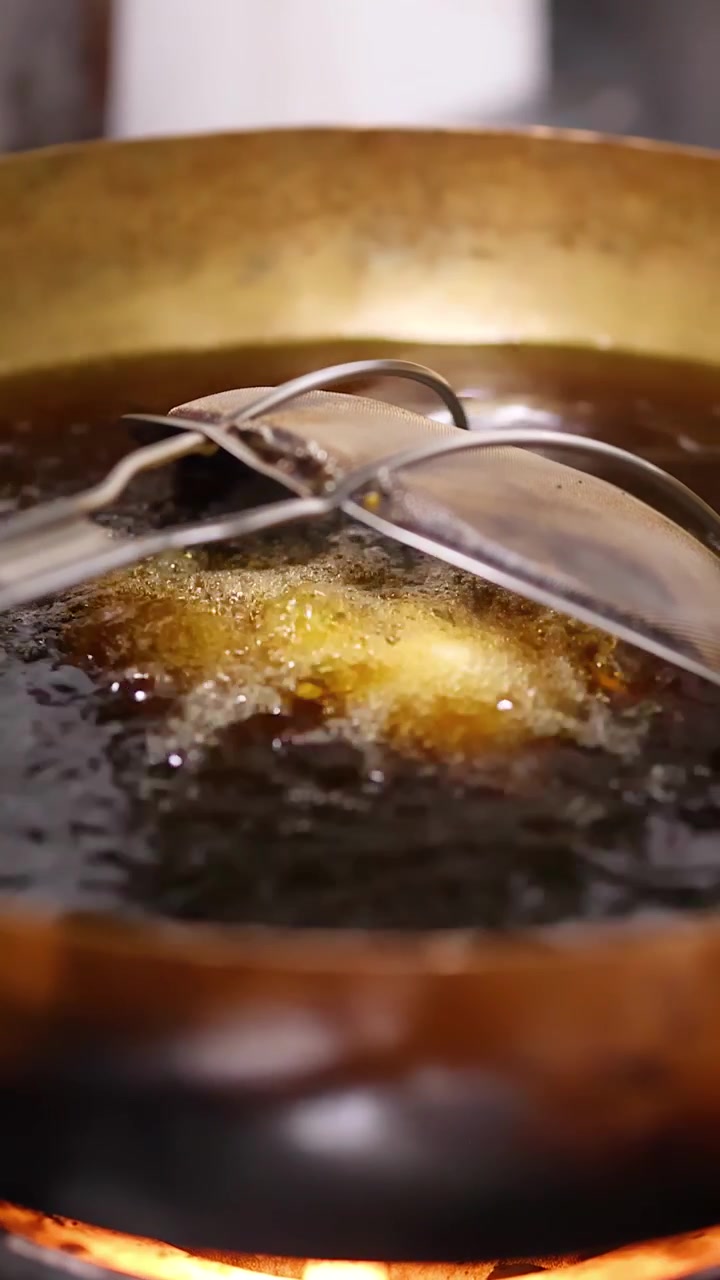 Primo piano di samosa indiani fritti in olio bollente in un wok tradizionale di ottone