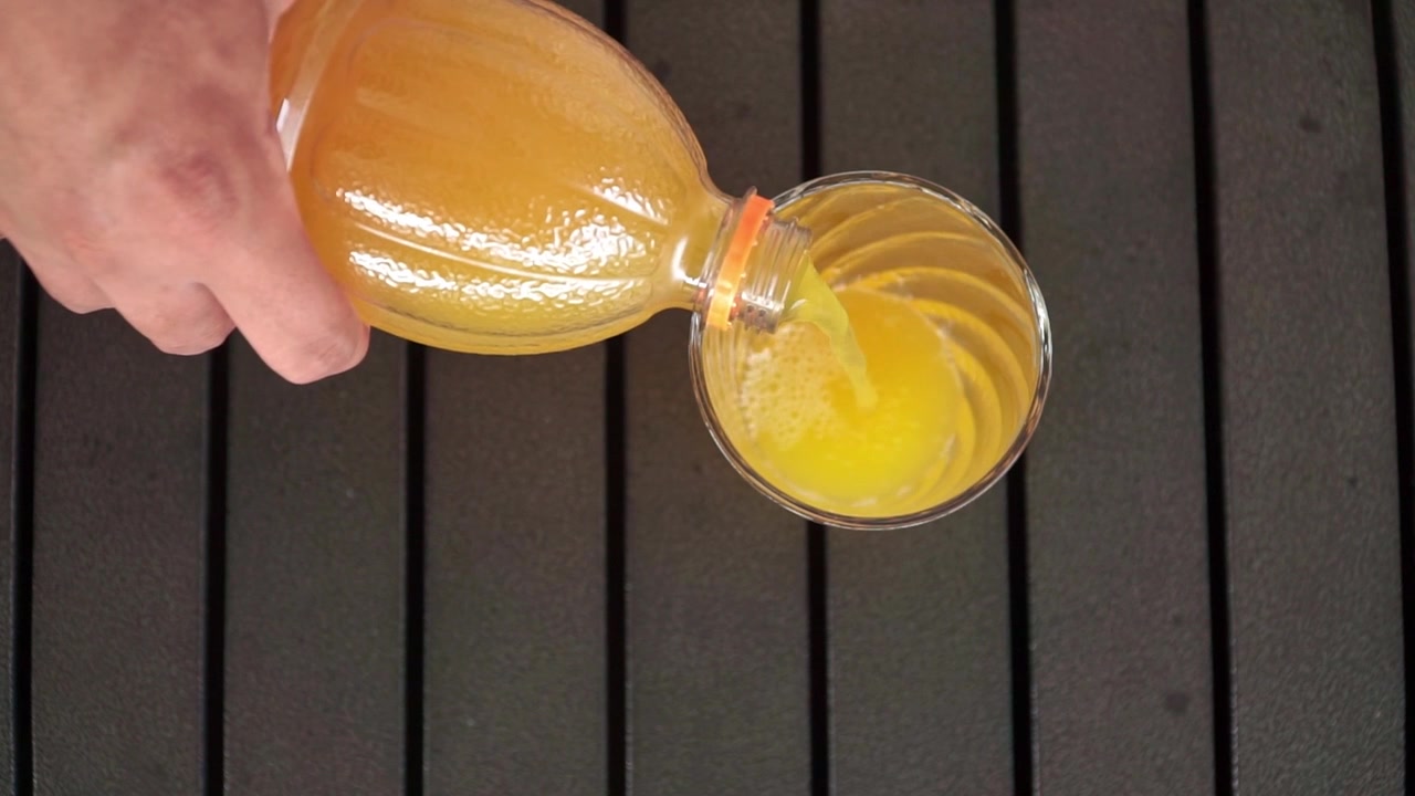 Zumo de naranja fresco siendo vertido en un vaso, concepto de bebida saludable con bebida cítrica refrescante y vitamina C natural.
