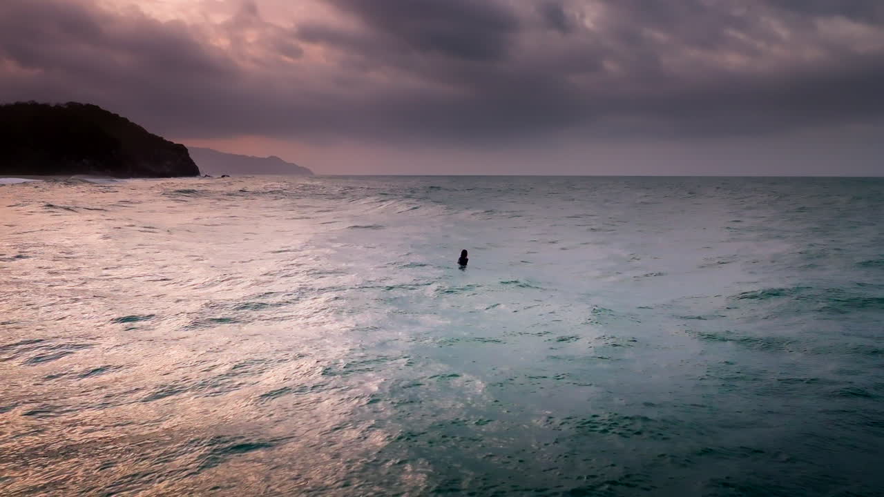 Silueta surfaře při západu slunce čekajícího na vlnu, Tayrona. Letecký