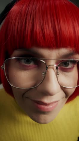 woman with red hair, glasses, and pink eyeshadow