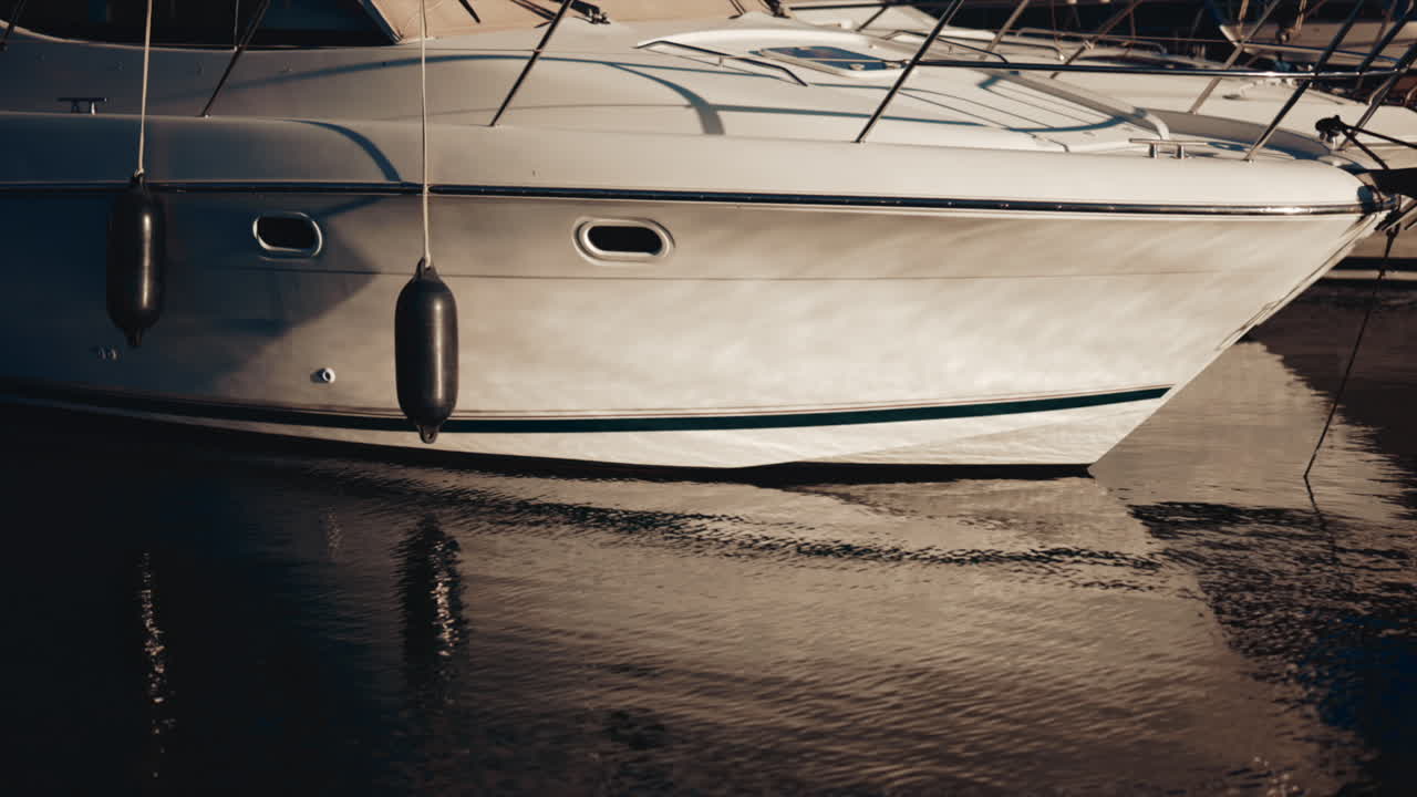 Primo piano di uno yacht bianco che riflette la luce del sole sull'acqua calma