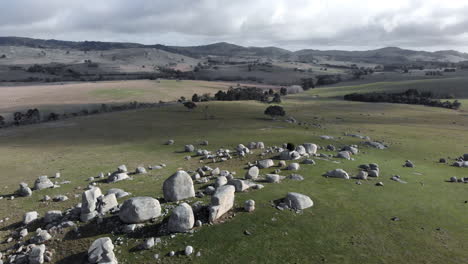 Aerial-rotation-circling-around-boulders-with-green-lush-landscape---mountain-horizon