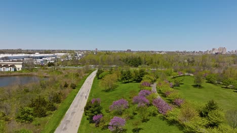 aerial flyover idyllic liberty state park with walking person in spring season during sunny day, nyc