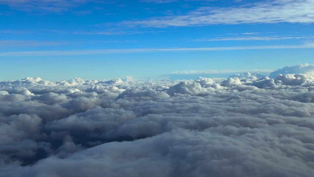 Pilot’s perspective from the cockpit of a jet airplane flying above an endless layer of stratus clouds at sunrise