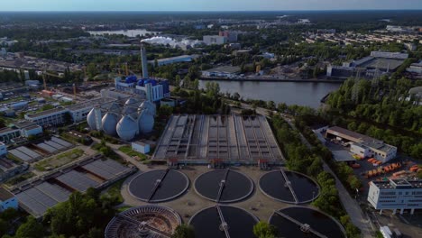 sewage treatment plant in berlin, featuring circular clarifiers, anaerobic digesters, and other wastewater processing infrastructure. best aerial view flight tilt down drone