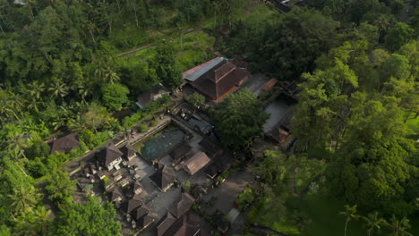 Inclinación-Aérea-Hacia-La-Vista-Superior-Del-Templo-De-Agua-Tirta-Empul-Balinés-Hindú-Con-Estanque-De-Agua-De-Manantial-Sagrado-Para-Bañarse.