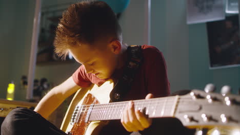 boy playing guitar in his bedroom