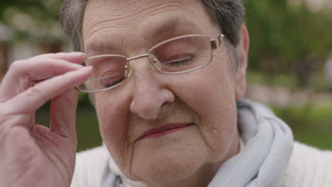 close up portrait of caucasian elderly woman removing glasses looking at camera