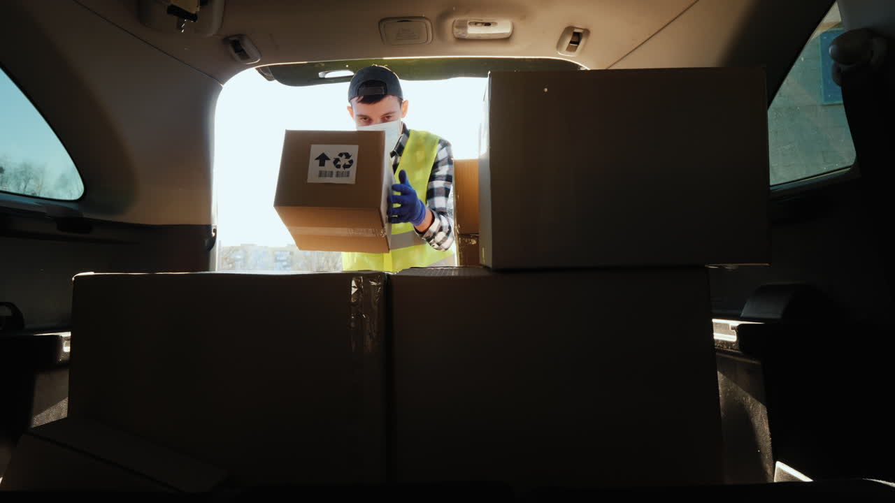 persona con una máscara carga cajas de medicamentos en el maletero del coche