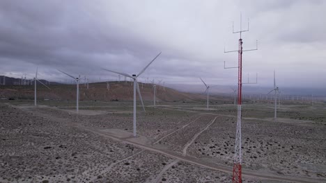 imágenes aéreas de un parque eólico en el desierto de palm springs en un día nublado, toma vertical lenta de carros
