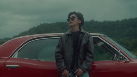 person standing next to a vintage red car