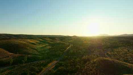 Sunrise-On-Horizon-Drone-Flyover-Simpson-Desert,-Outback-Australia-With-Rural-Highway-And-Mountains,-4K