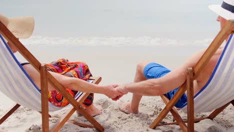 Retired-couple-holding-hands-on-deckchairs