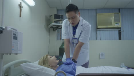 medical student intern explaining and demonstrating cpr on mannequin lying on hospital bed